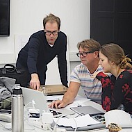 
                                Zwei Professoren und eine Studentin, die ein Projekt diskutieren
                            