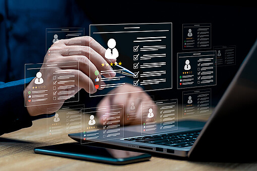 
                Person sitzt vor Laptop mit einem Stift in der Hand und schreibt auf eine transparente Tafel, welche auf dem Laptop steht.
            