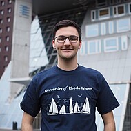 
                                Male student smiling in front of university building
                            