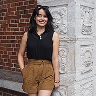 
                                female student Standing in front of a Campus building    
                            