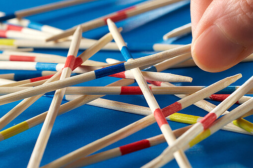 
                Person hält ausgebreitete Mikadostäbchen in der Hand
            