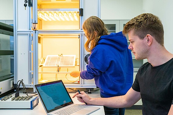 
                                Zwei Studenten bedienen die eine Messstation für Solarzellen
                            