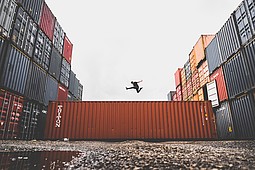 Nutzung agiler Methoden in traditionellen Logistikunternehmen und Logistikstartups
Zwischen Containerreihen rechts und links ist ein Container quer sichtbar und darüber eine springende Person.